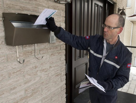 Letter carrier Richard Autotte delivers mail in the east end of Montreal Thursday, March 5, 2015. Police are investigating a series of robberies on letter carriers by thieves who have been taking the carriers keys to community and apartment mailboxes. THE CANADIAN PRESS/Ryan Remiorz